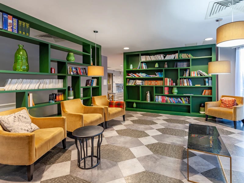 Velvet armchairs and green bookshelves lounge area at The Fitzalan in Cardiff Student Accommodation