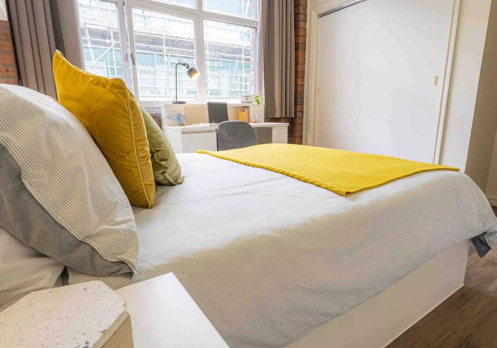 Bed with yellow pillows and desk area bedroom at iQ Hollingworth House in Manchester Student Accommodation