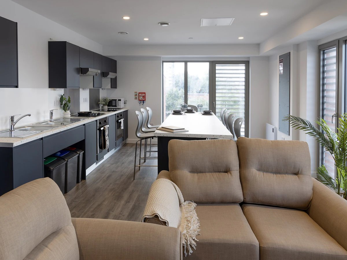 Sofa kitchen island bar stools and dining table living room at The Terry Frost Building in Leeds Student Accommodation