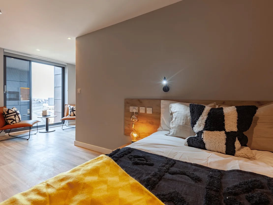 Bed pillows lamp chairs table window bedroom at Benson Yard in Liverpool Student Accommodation