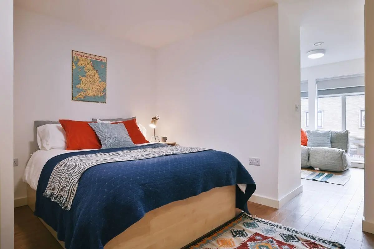 Map on wall bed blue blanket red pillows bedroom at Pavilion Court in Canterbury Student Accommodation