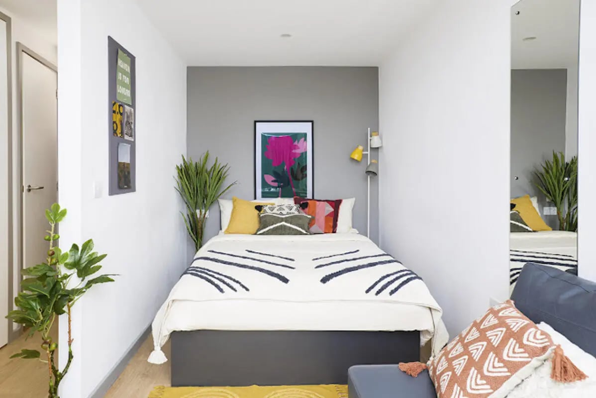 Bed with colorful pillows artwork plants and mirror bedroom at Staniforth House in Birmingham Student Accommodation