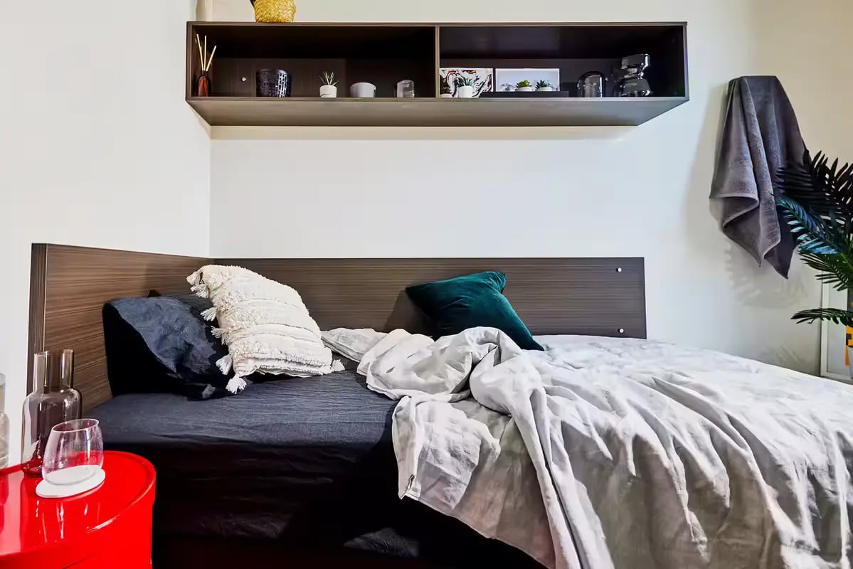 Bed with white and green pillows shelf bedroom at Scape Quay in Sydney Student Accommodation