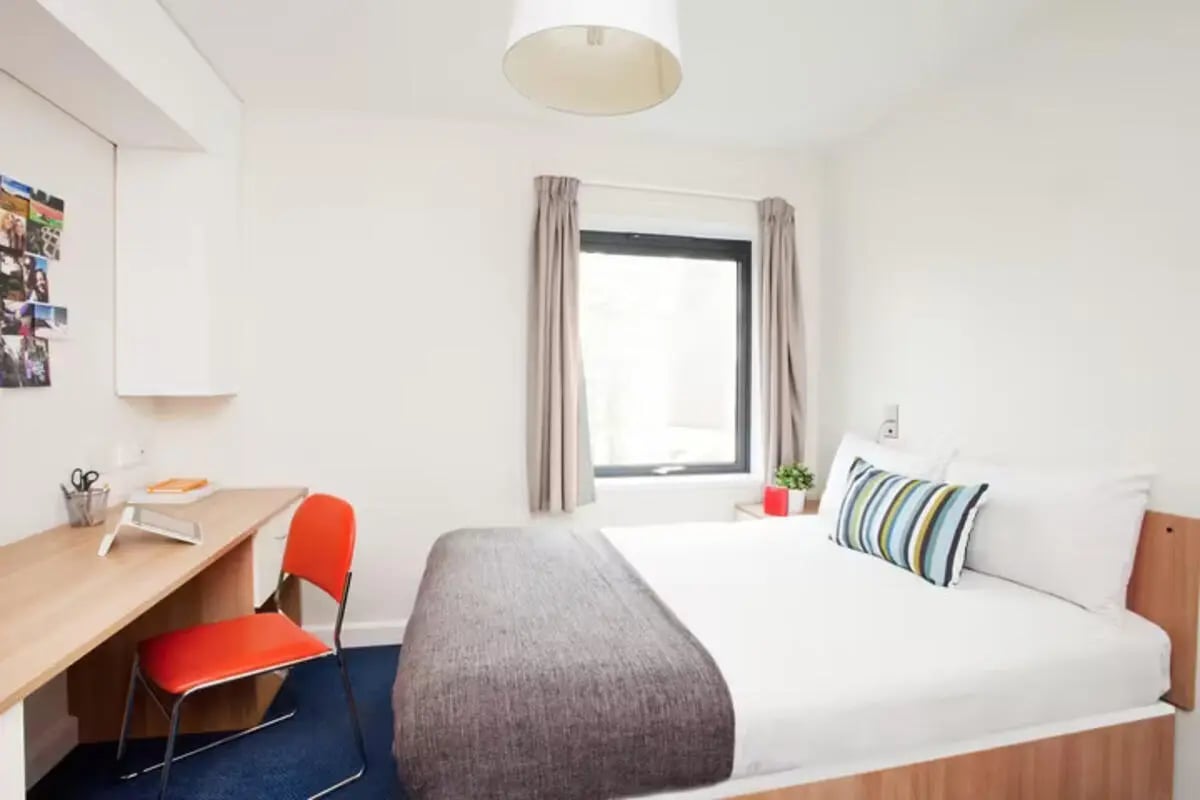 Desk bed and orange chair bedroom at Dorset House in Oxford Student Accommodation