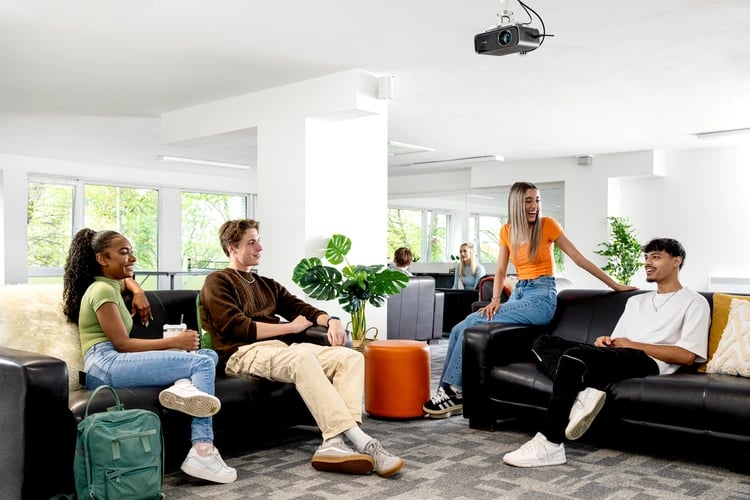 Four students relaxing on black sofas living room at Liberty Park in Leicester Student Accommodation