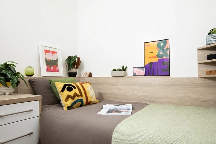 Bed with pillows artwork and plants bedroom at Arbour House in London Student Accommodation