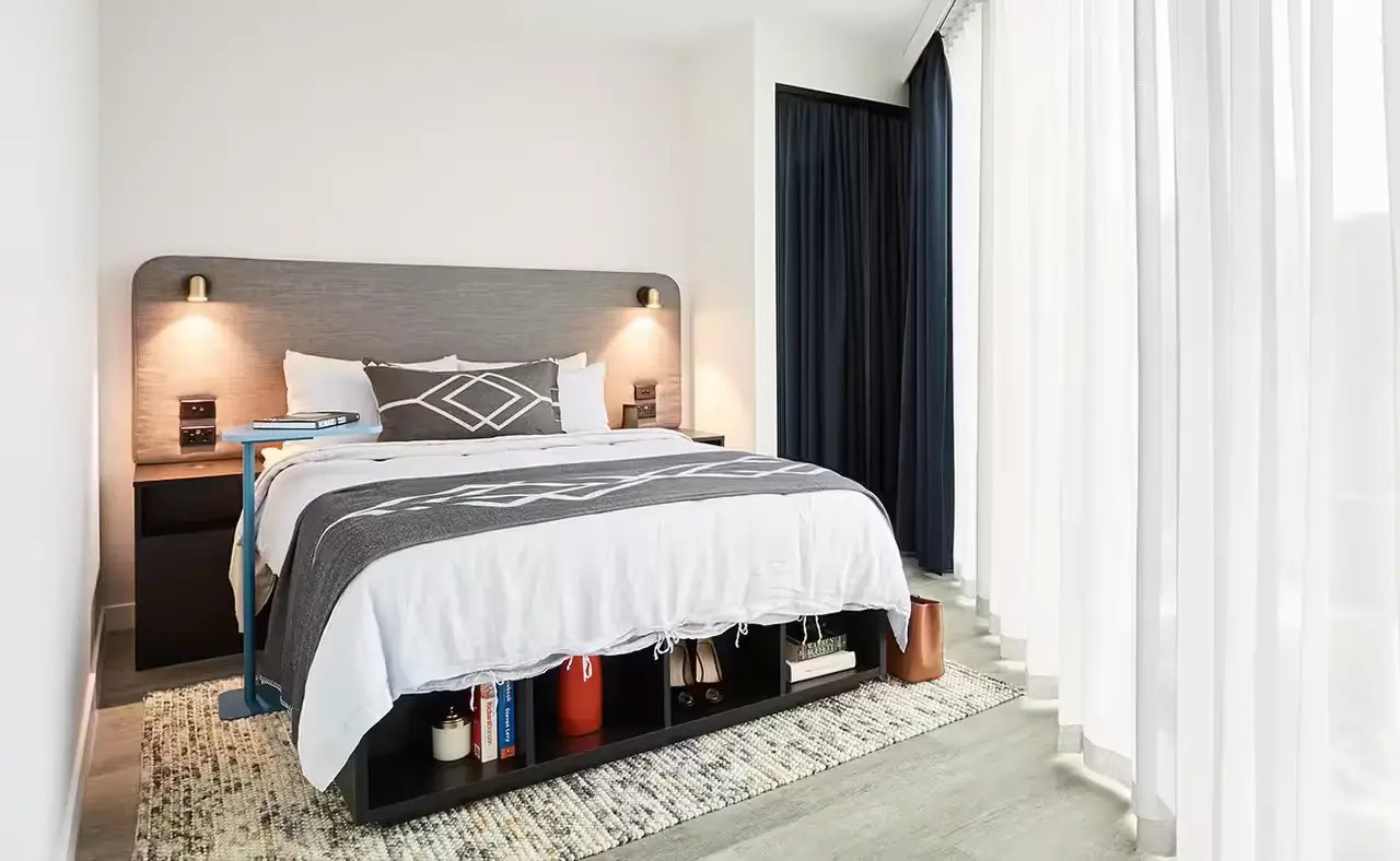 Bed with storage nightstand and curtains Bedroom at Scape Aurora in Melbourne Student Accommodation