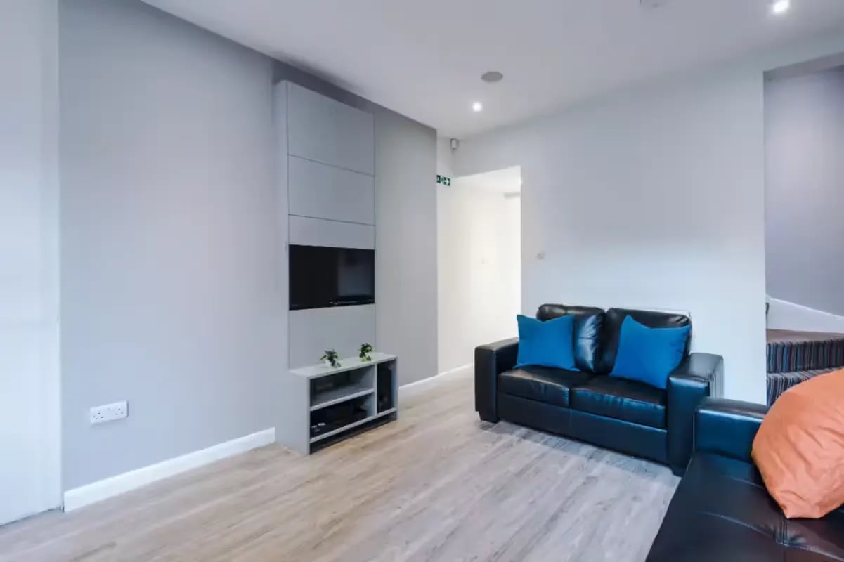 Black sofa with blue cushions and TV living room at 32 Cauldon Road in Stoke-On-Trent Student Accommodation