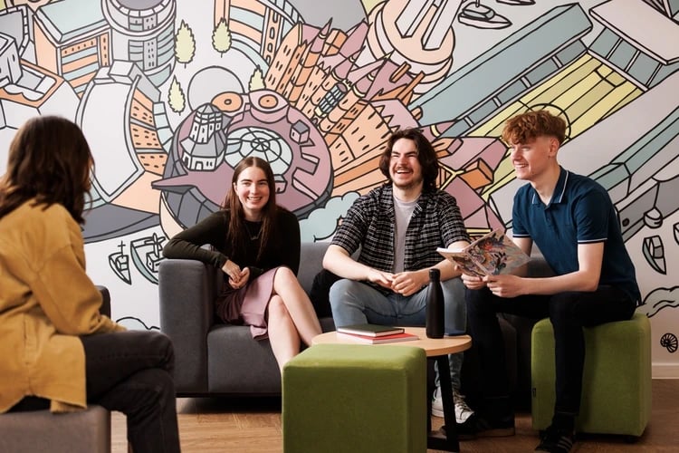 Four students on couches with colorful wall living room at Chaucer House in Portsmouth Student Accommodation