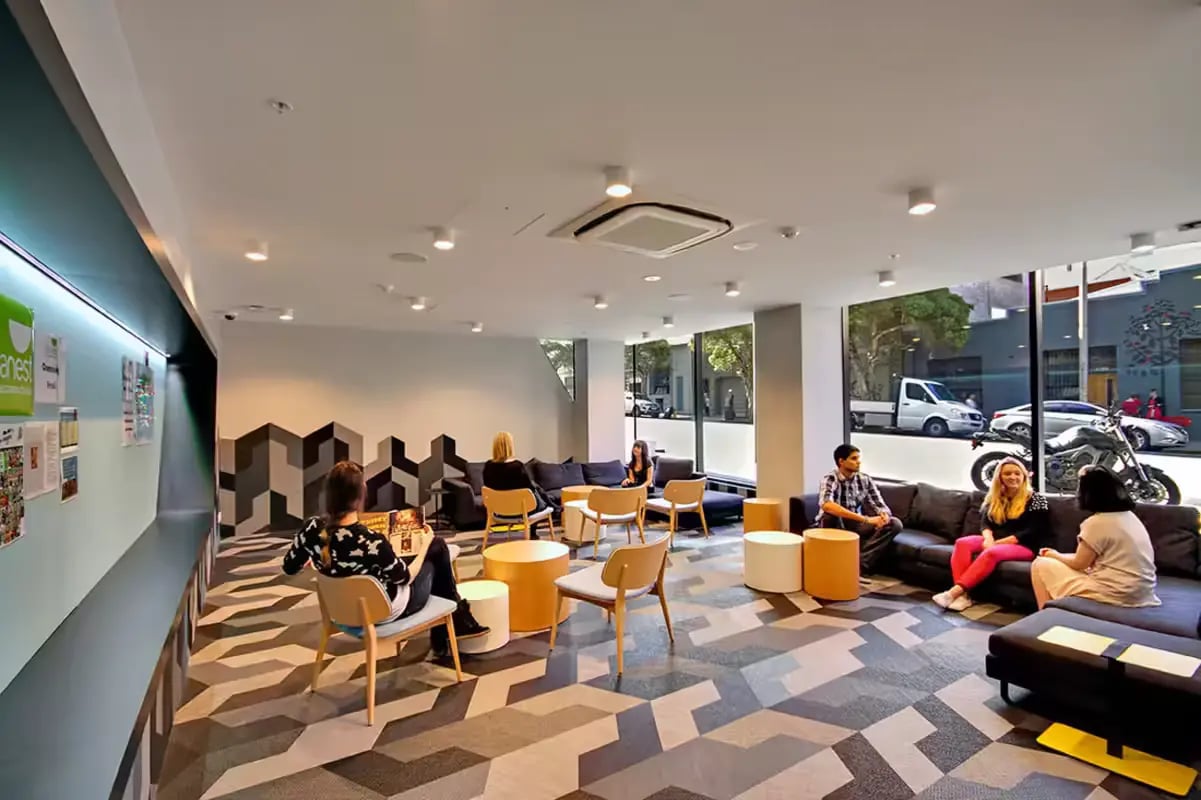 Students relaxing in modern communal lounge living room at Scape Berkeley in Melbourne Student Accommodation