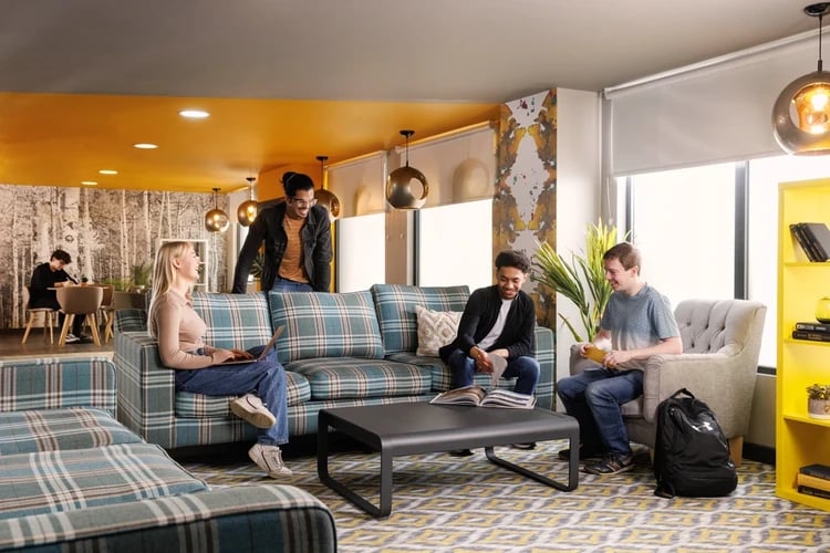 Students chatting on plaid sofas in a common area at Brass Founders in Sheffield Student Accommodation