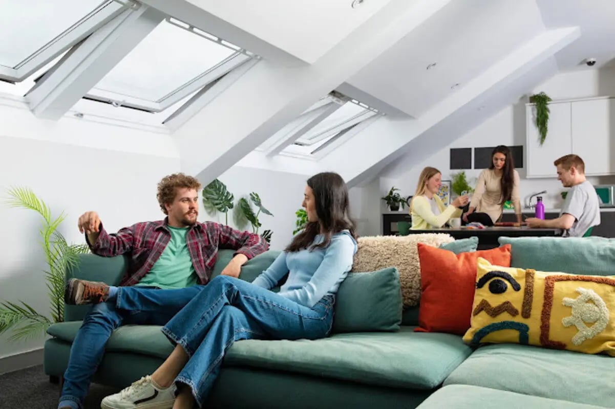 People relaxing on couch with kitchen area living room at Tramworks in Glasgow Student Accommodation