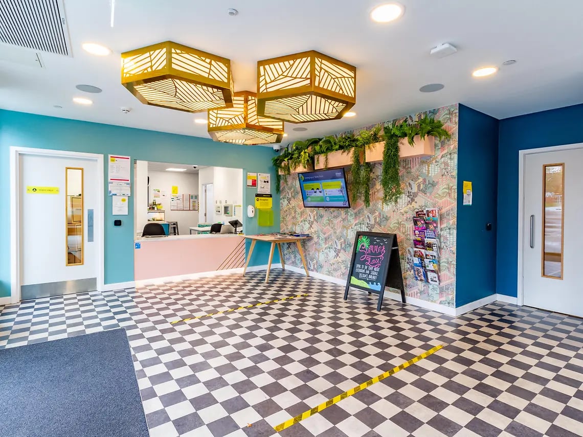 Reception desk with checkered floor and plants interior at Yugo Belaton House in Bournemouth Student Accommodation