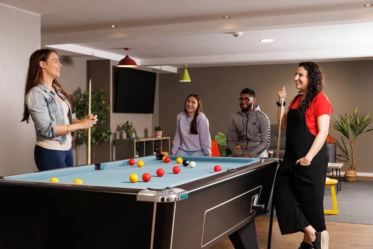 Students playing billiards around a pool table Recreation area at Manor Bank in Newcastle Upon Tyne Student Accommodation