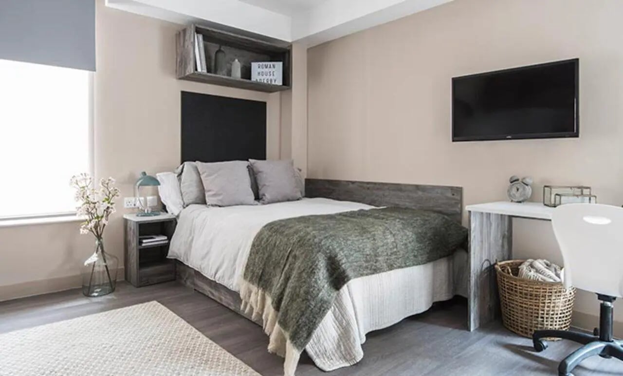Bed with pillows blanket desk TV bedroom at Collegiate Roman House in Derby Student Accommodation