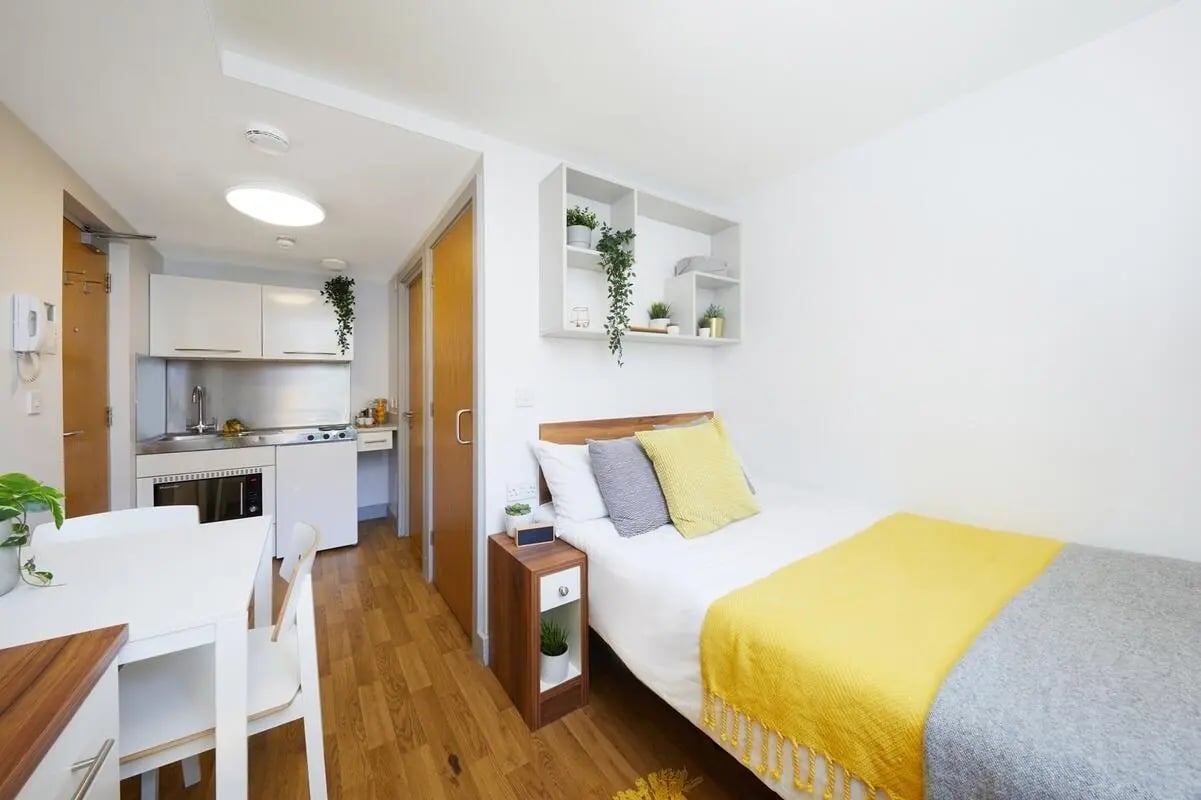 Bed kitchen dining table with plants bedroom studio at Collegiate St James Street in Portsmouth Student Accommodation