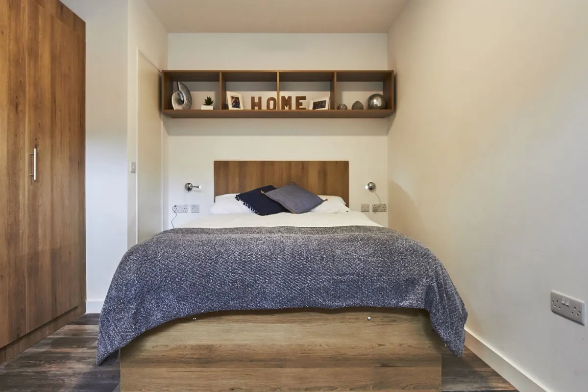 Bed with grey blanket and wooden wardrobe bedroom at City Heights - Cardiff in Cardiff Student Accommodation