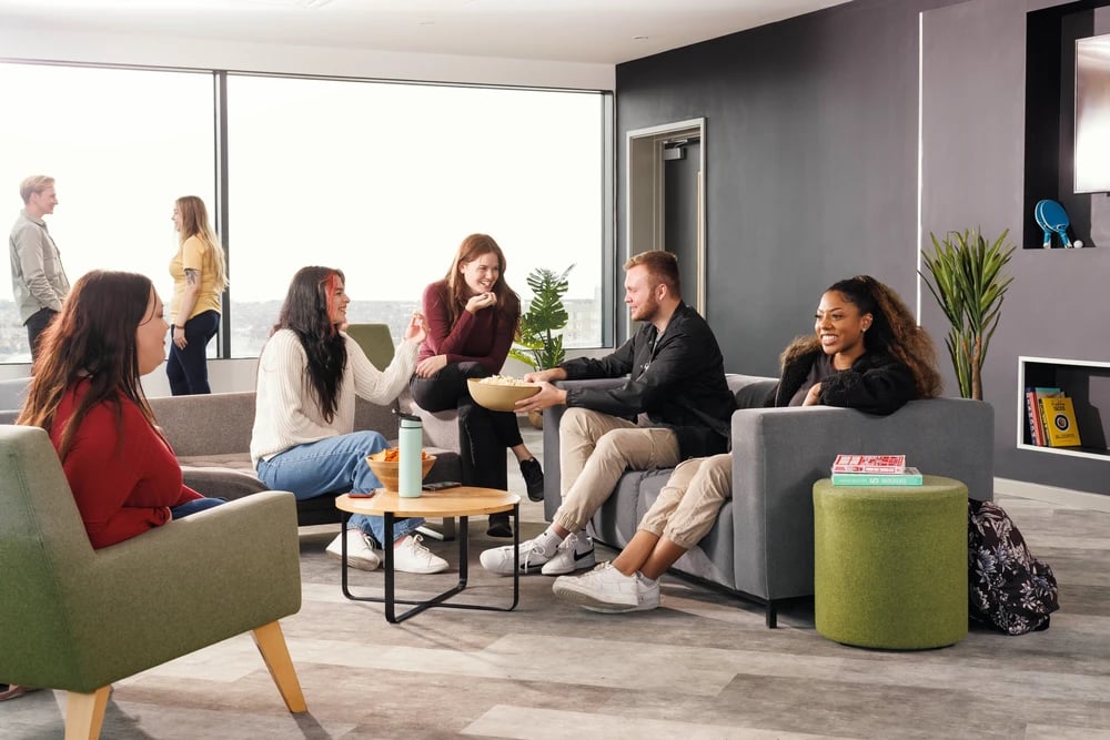 Students chat on couches with popcorn and drinks living area at Greetham Street in Portsmouth Student Accommodation