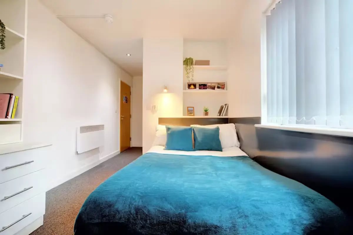 Bed with teal blanket and pillows bedroom at Brookland Road in Leicester Student Accommodation