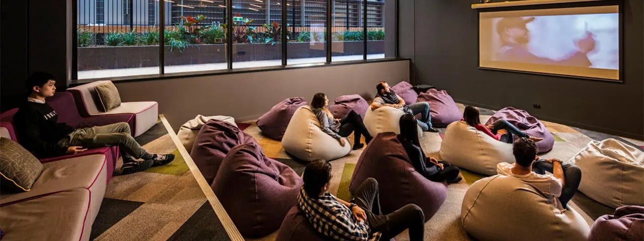Beanbag chairs and sofas facing projector screen movie area at Student One Adelaide Street in Brisbane Student Accommodation