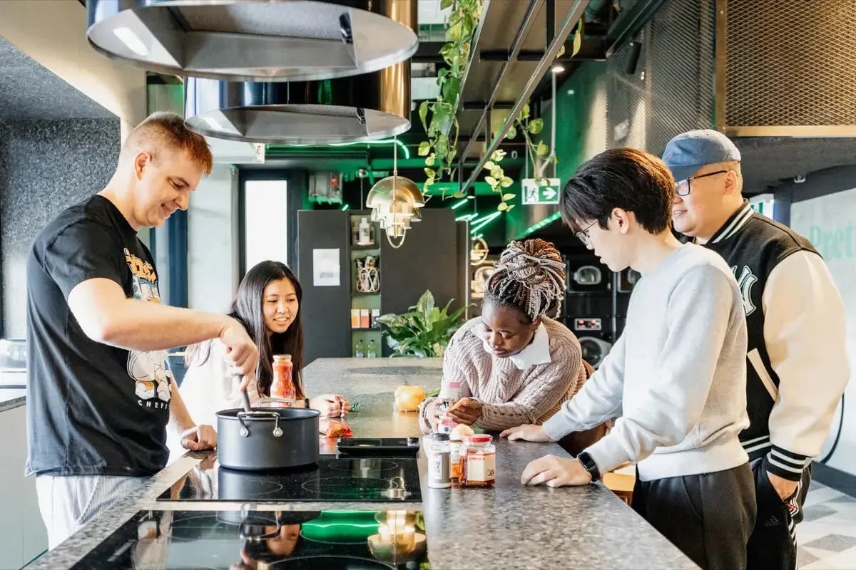 Students cooking and chatting at a kitchen island kitchen at Perth Central in Perth Student Accommodation