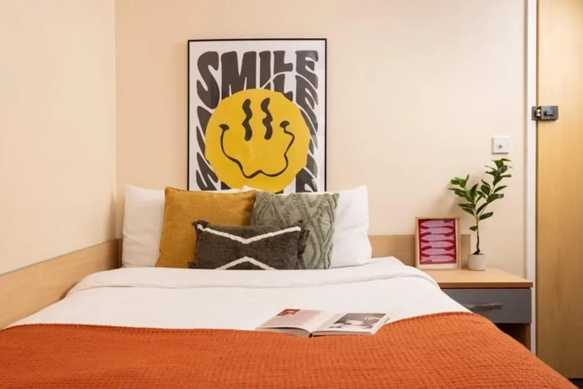 Bed with orange blanket and smile poster bedroom at Lennon Studios in Liverpool Student Accommodation