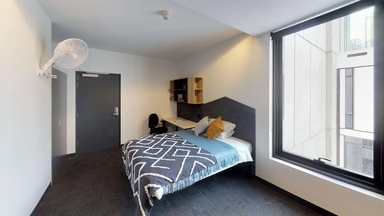 Bed desk fan and wall shelves bedroom at UniLodge Lincoln House in Melbourne Student Accommodation