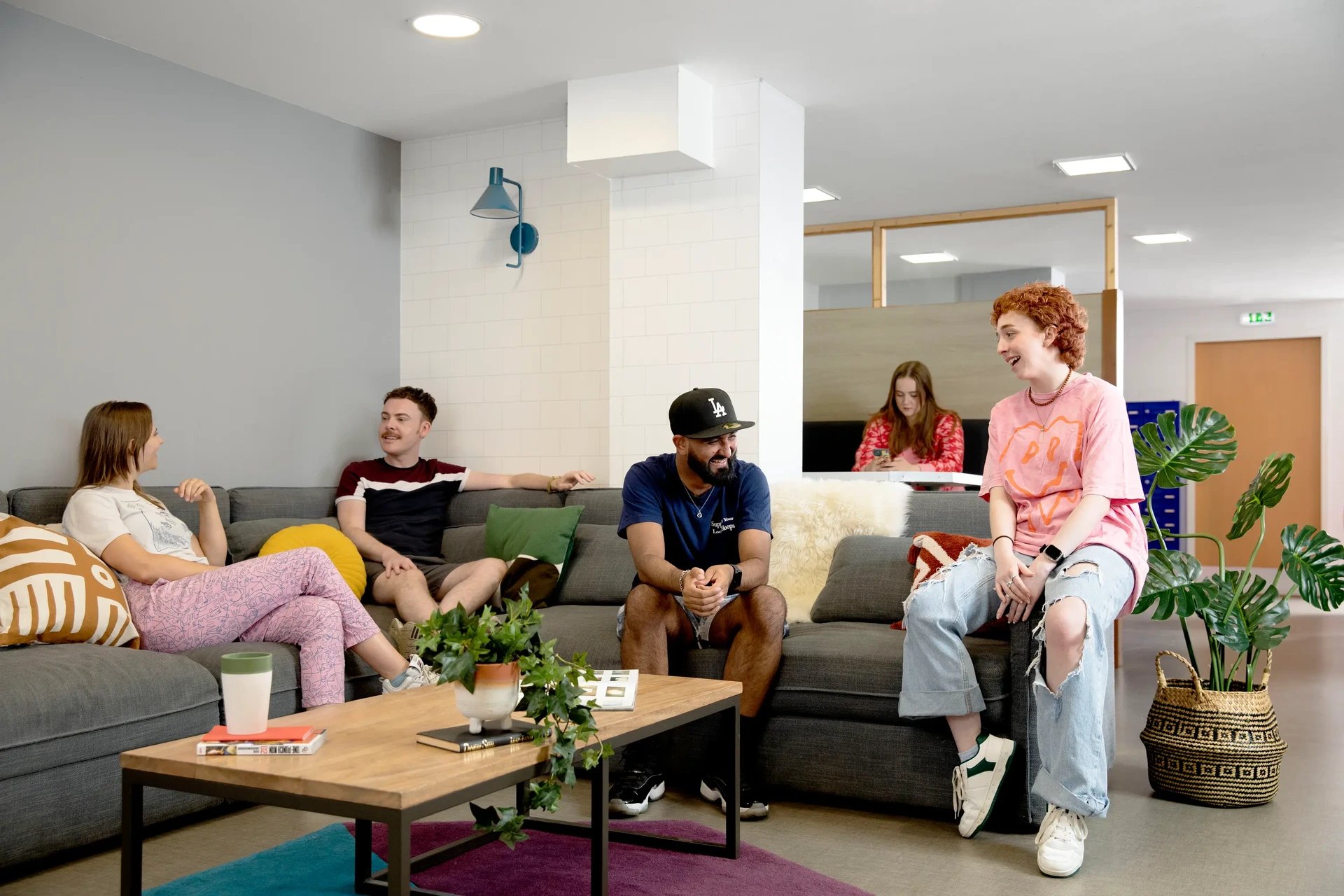 Students chatting on sofas in a communal living room at Ty Pont Haearn in Cardiff Student Accommodation