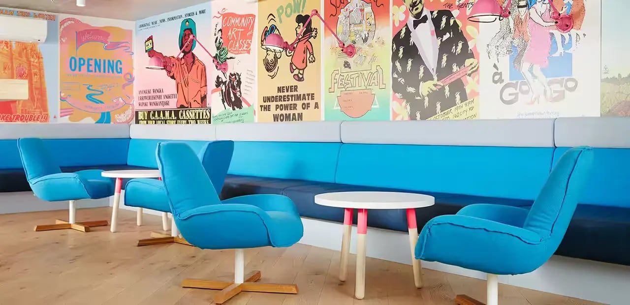 Blue chairs small tables colorful posters common area at Scape Abercrombie in Sydney Student Accommodation