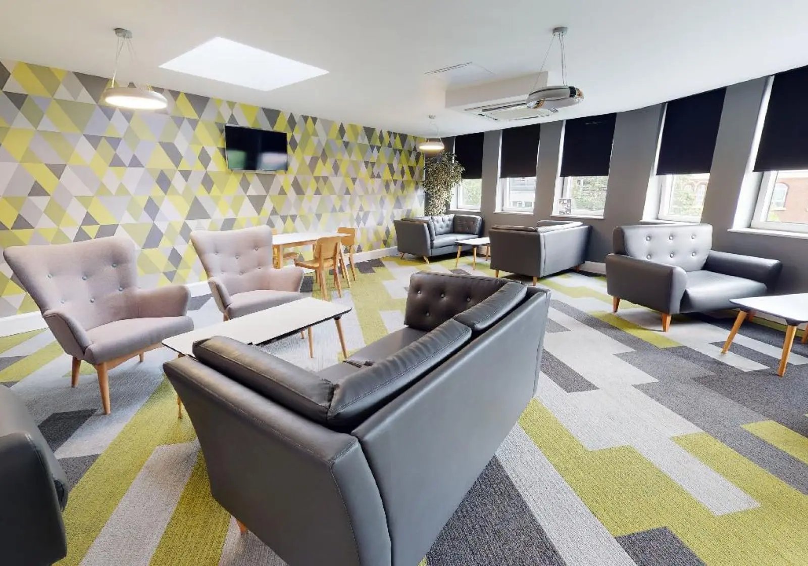 Sofas armchairs tables TV and patterned walls common area at iQ Newtown House in Nottingham Student Accommodation