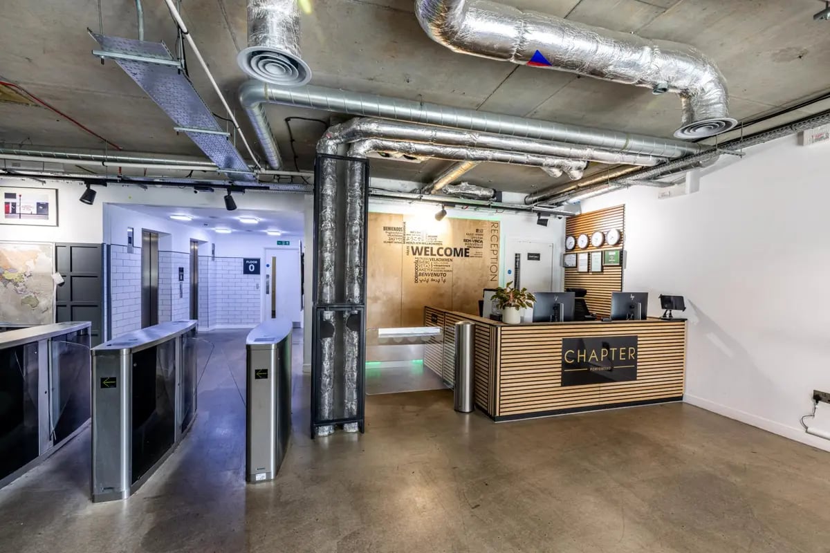 Reception desk with computers and welcome wall Reception Area at Chapter Portobello in London Student Accommodation