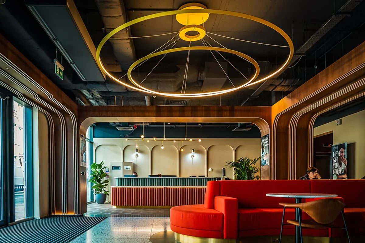 Red sofa reception desk plants chandelier lobby at Chapter Old Street in London Student Accommodation