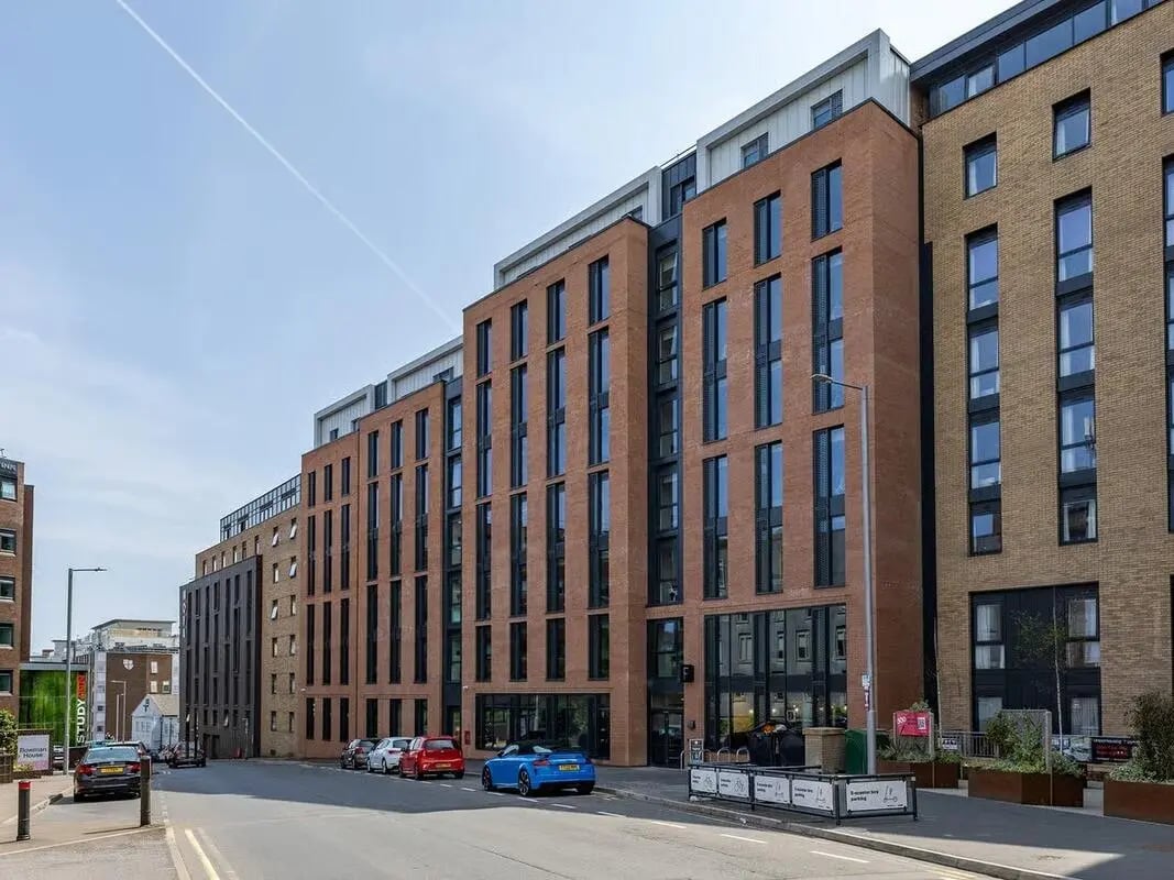Modern brick buildings with cars parked outside exterior at Fabric in Nottingham Student Accommodation