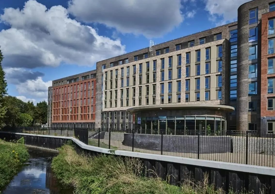 Modern student accommodation exterior with river and trees at Deakins Place in Nottingham Student Accommodation