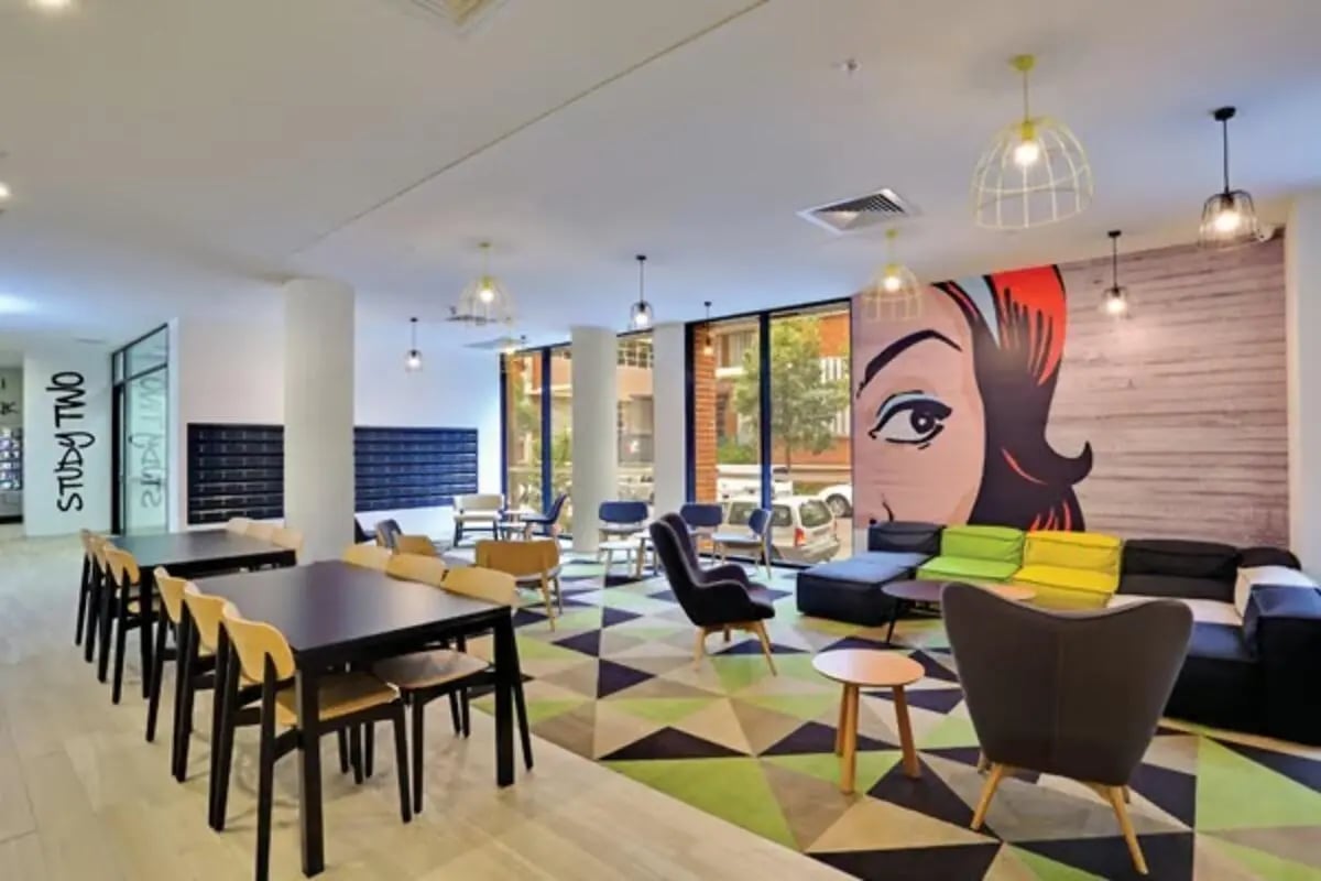 Student lounge with tables chairs and colorful artwork lounge area at Scape Sydney Central in Sydney Student Accommodation