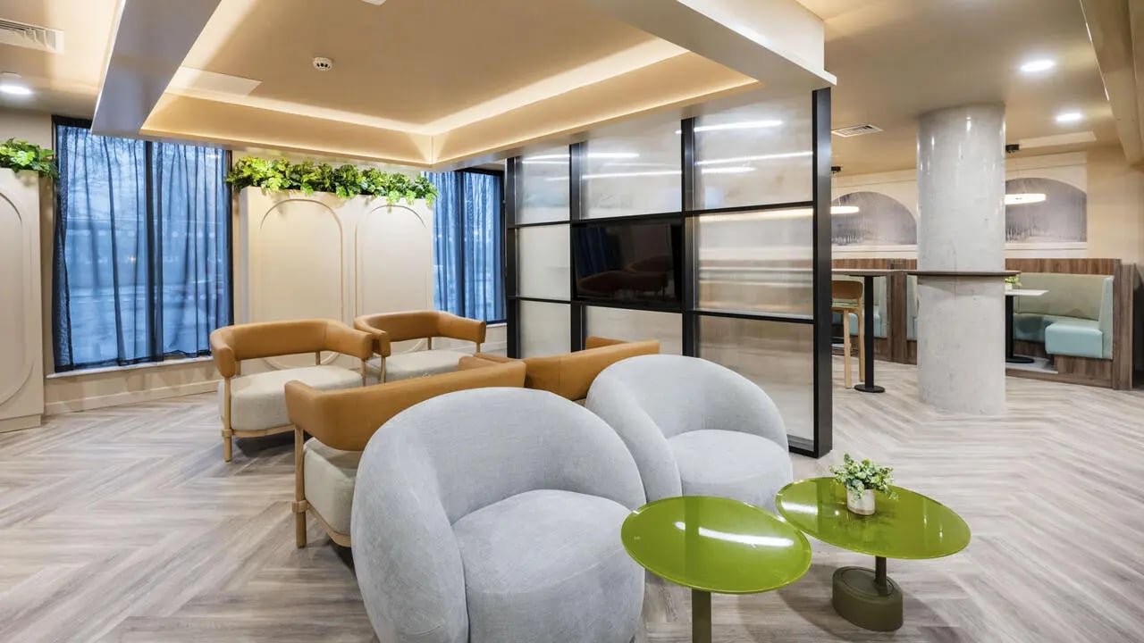 Modern seating area with green tables and TV living room at The Sail Works in Lancaster Student Accommodation