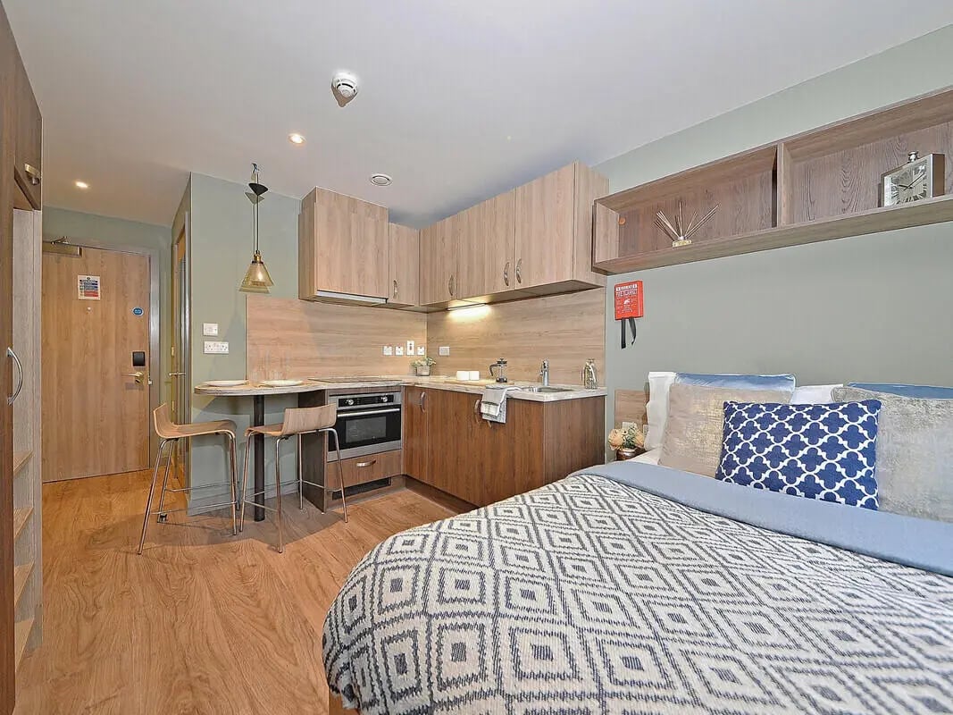 Bed kitchen area with oven and stools Studio bedroom at Fontenoy Apartments in Liverpool Student Accommodation