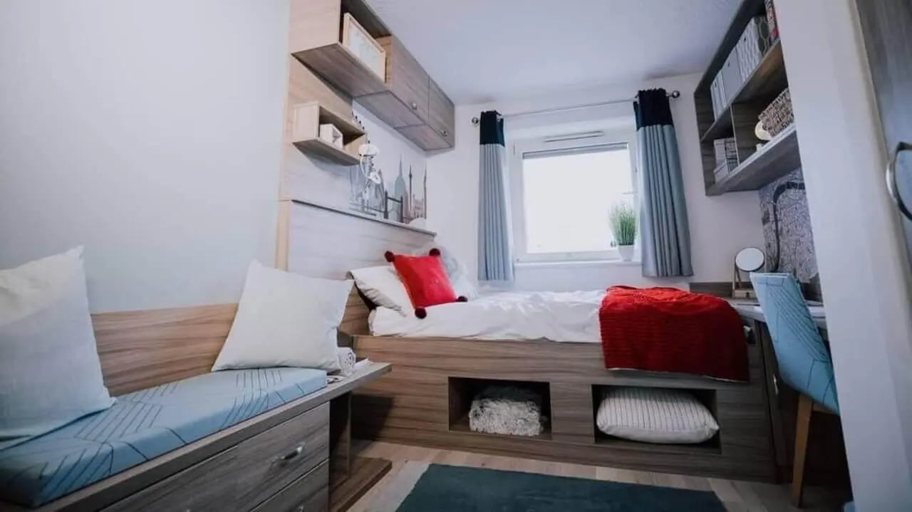 Bed with red blanket and pillows bedroom at Manna Ash House in London Student Accommodation