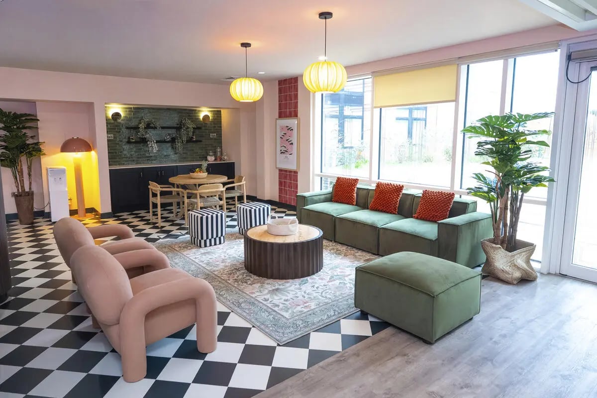 Green sofa orange pillows striped stools living room at Aparto Arbury Court in Kingston Upon Thames Student Accommodation