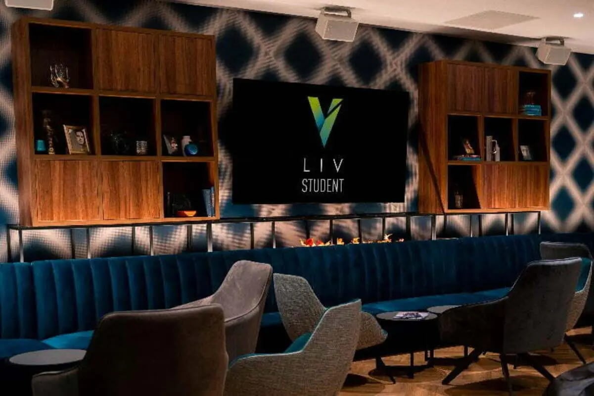 Blue couch TV and wooden shelves common area at LIV Student Belfast in Belfast Student Accommodation