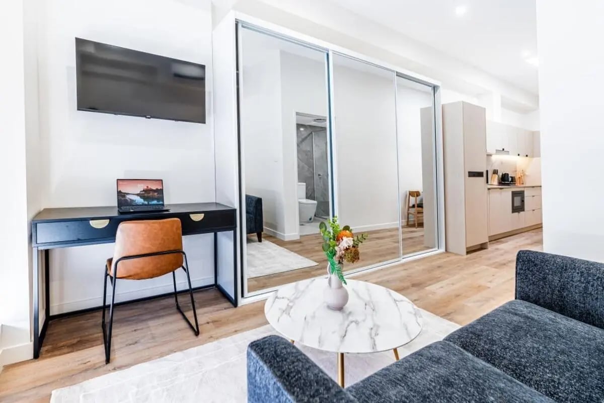 Desk chair TV laptop mirrored wardrobe living area kitchen at UKO Annandale Tower C in Sydney Student Accommodation