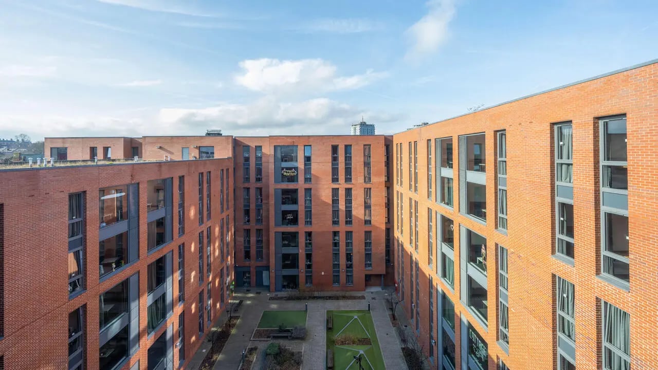 Courtyard with brick buildings green grass and benches exterior at The Elements in Sheffield Student Accommodation