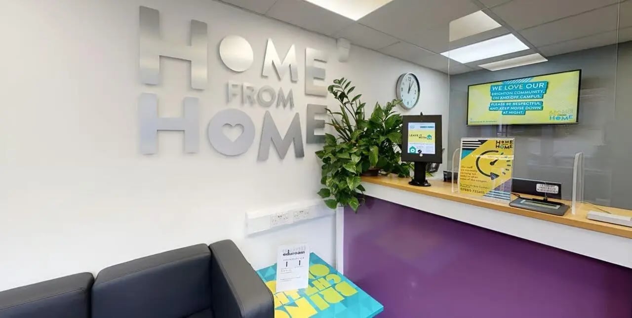 Reception desk with plants and signage interior reception at Moulsecoomb Place in Brighton Student Accommodation