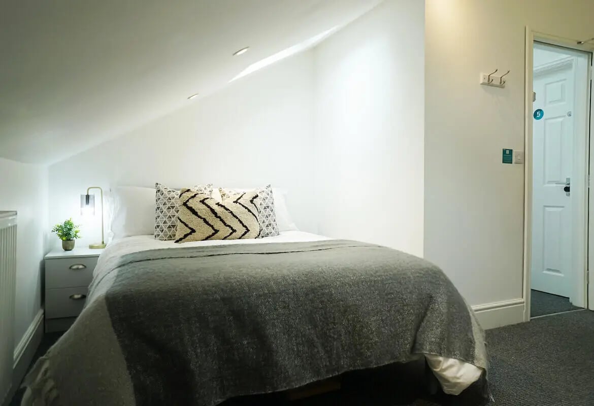 Bed with decorative pillows and bedside table bedroom at 5 Bedroom House at 19, Driffield Street in Manchester Student Accommodation