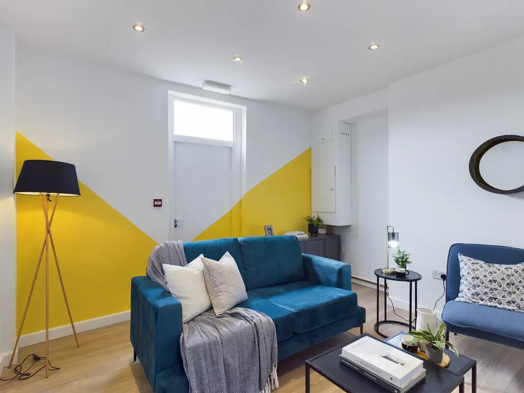 Blue sofa with throws and pillows living room at 8 Bedroom House at 4, Ossory Street in Manchester Student Accommodation