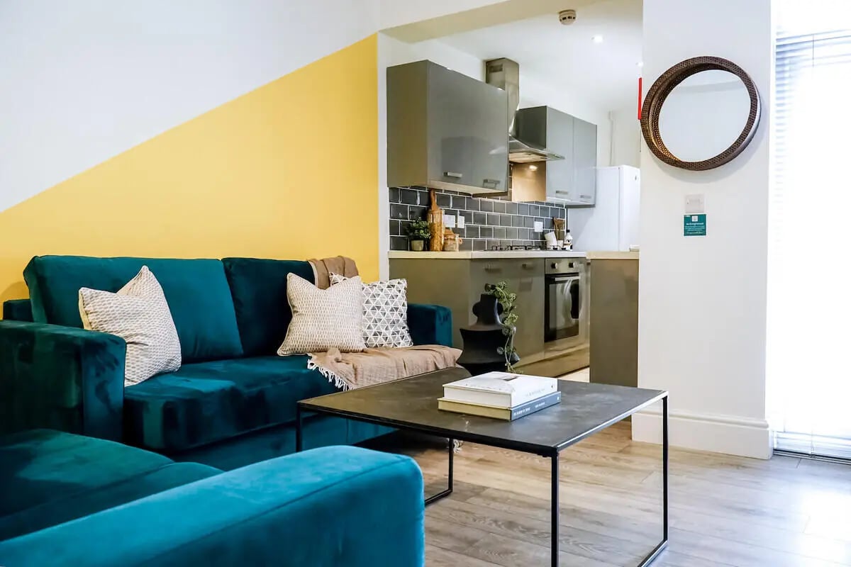 Teal sofa with pillows coffee table living room at 6 Bedroom House at 49, Ruskin Avenue in Manchester Student Accommodation
