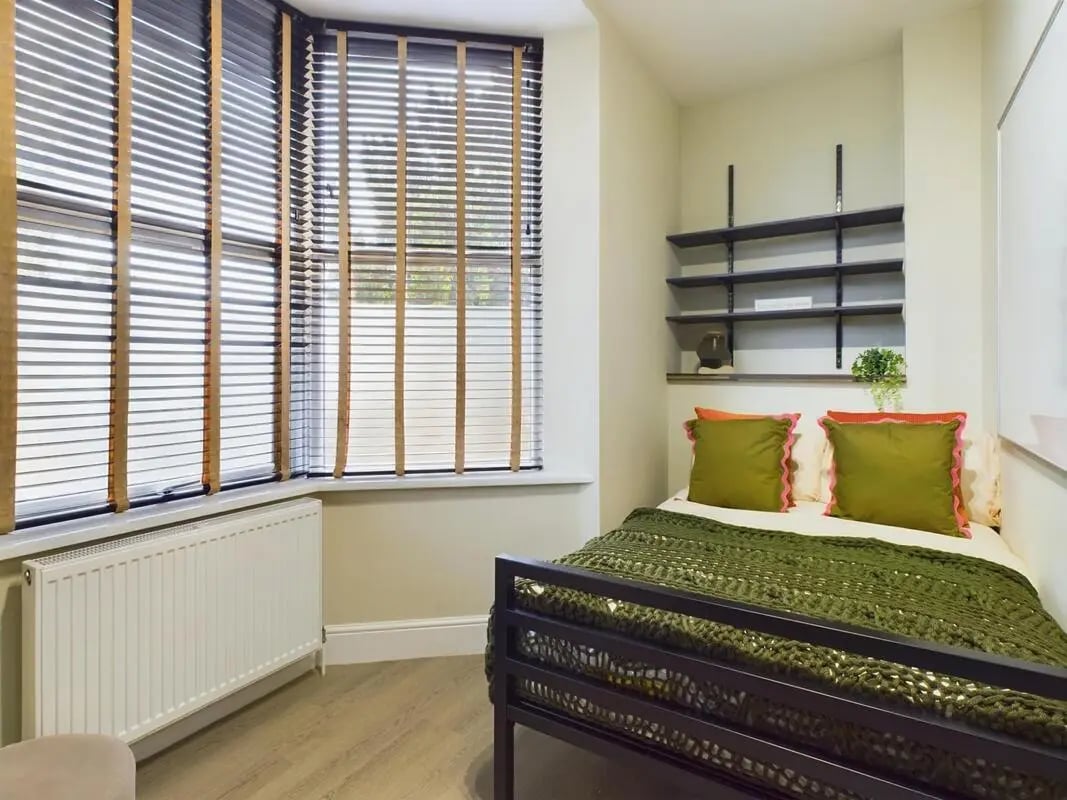 Bed with green knit blanket two green pillows shelves bedroom at 7 Bedroom House at 19, Studios at, St. Catherines in Lincoln Student Accommodation
