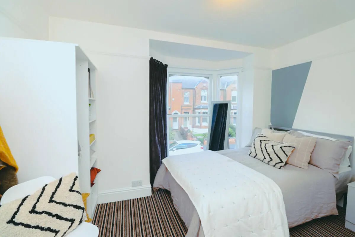 Bed with pillows bookshelf and window bedroom at 5 Bedroom House at 71A, West Parade in Lincoln Student Accommodation