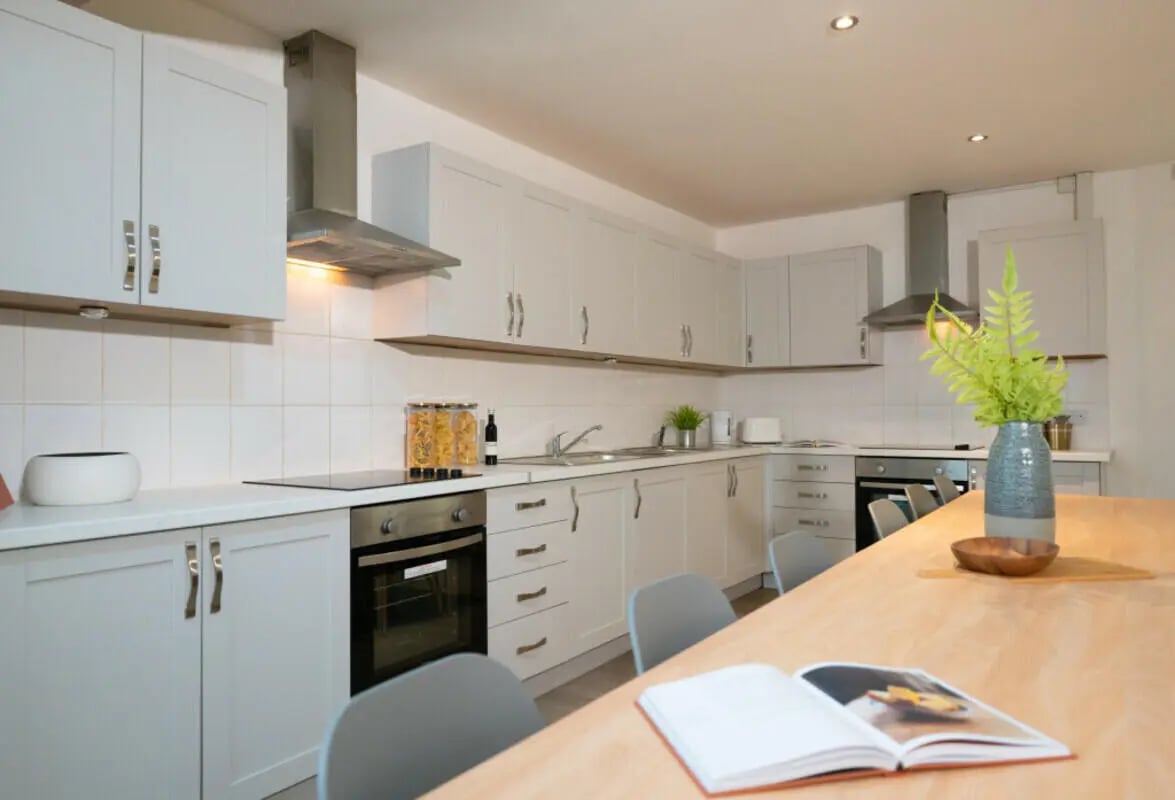 Modern kitchen with white cabinets oven and dining table kitchen at 3 Bedroom House at Flat 2, 331, Dickenson Road in Manchester Student Accommodation