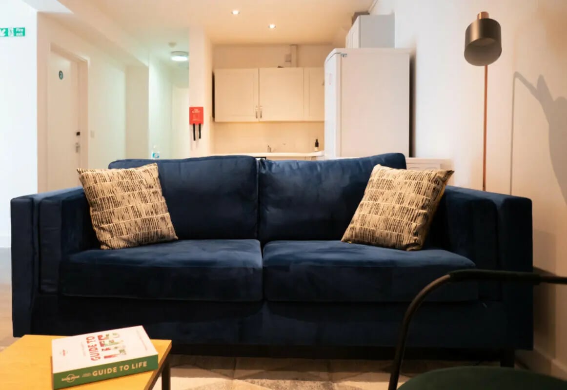 Blue sofa with pillows kitchen and lamp living room at 6 Bedroom House at 5, ASHFIELD ROAD in Manchester Student Accommodation